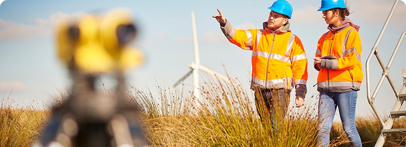 Deux professionnels en train d'estimer les risques et les contraines d'un terrain en le visitant